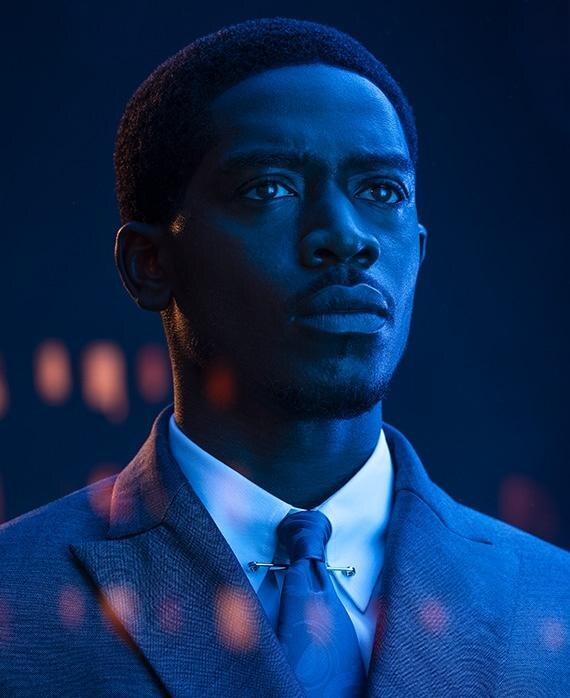 Franklin Saint, lit in deep blue, looking past the camera.